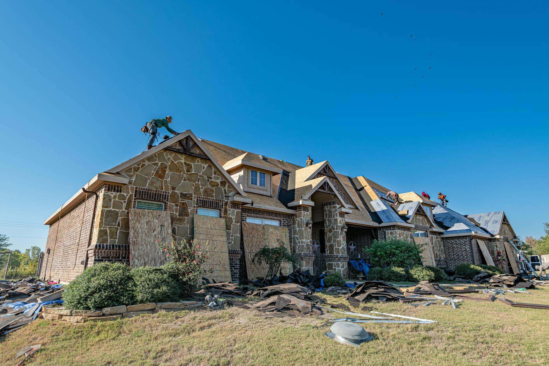 Stone house with its roof torn away and debris scattered across the lawn